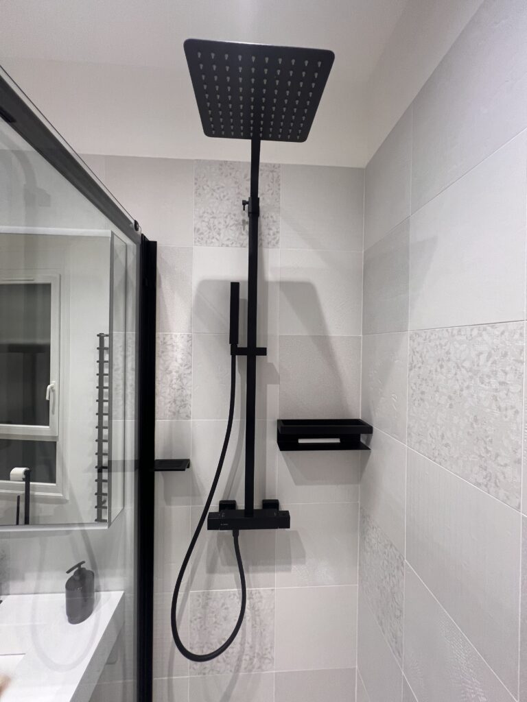 Gros plan sur une colonne de douche noire avec douchette et ciel de pluie, installée à Saint-Mandé.