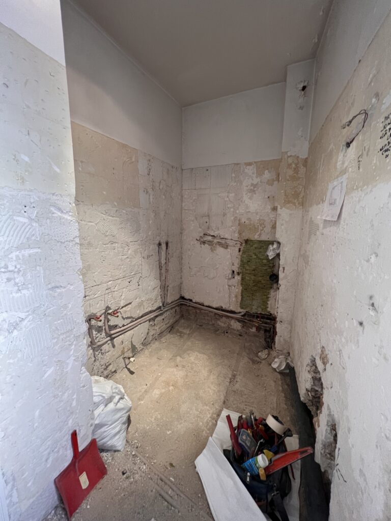 Vue du chantier d’une salle de douche en rénovation à Saint-Mandé, avec murs mis à nu et installation de la nouvelle plomberie en cours.