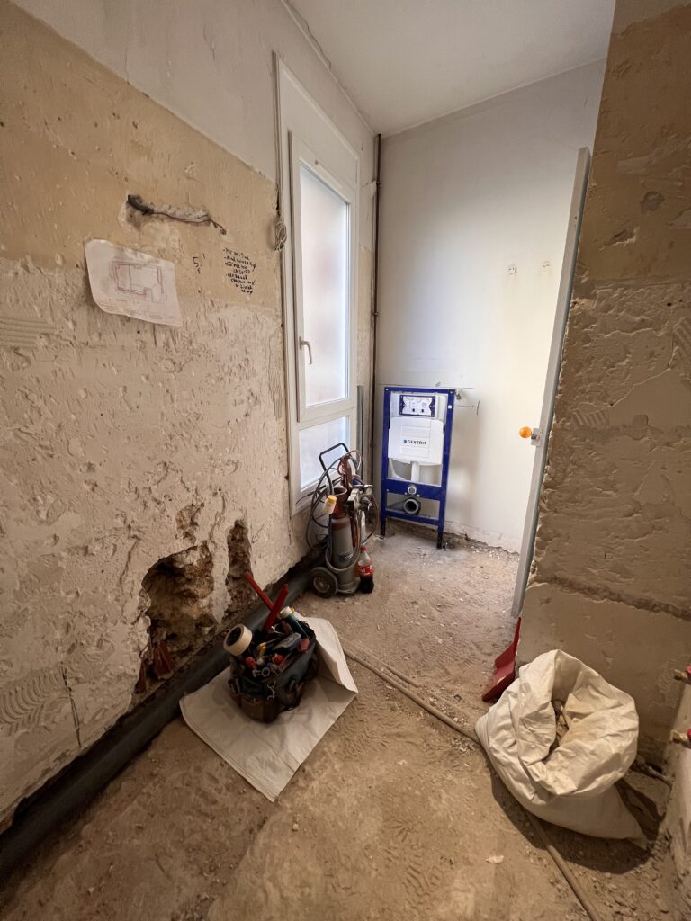 Vue du chantier en cours dans une salle de douche en rénovation à Saint-Mandé, avec mur mis à nu et préparation des installations.