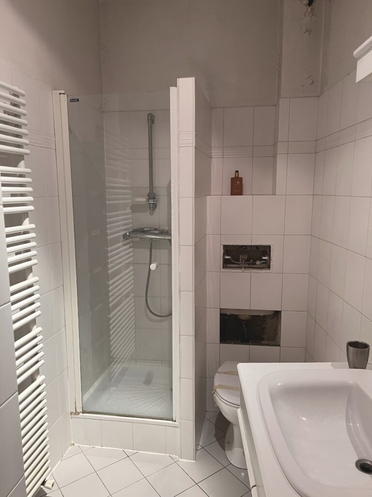 Vue générale d’une salle de douche avant rénovation à Saint-Mandé, avec des équipements anciens et des finitions abîmées.