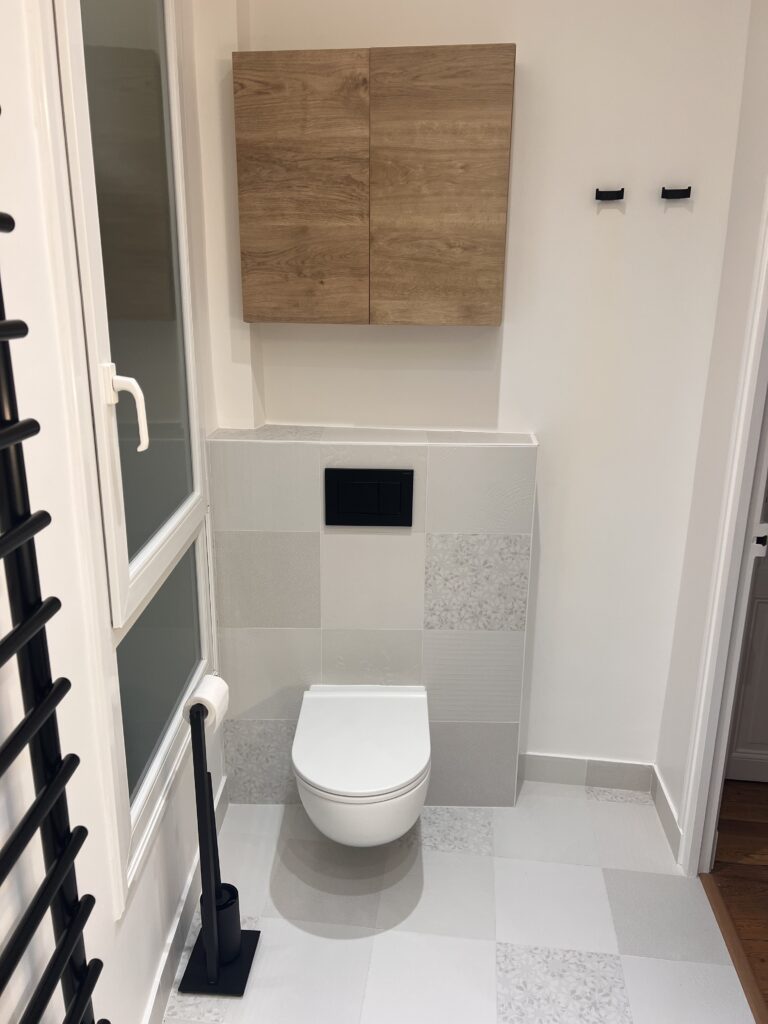 Vue des WC suspendus à Saint-Mandé, avec carrelage structuré et meuble de rangement en bois.