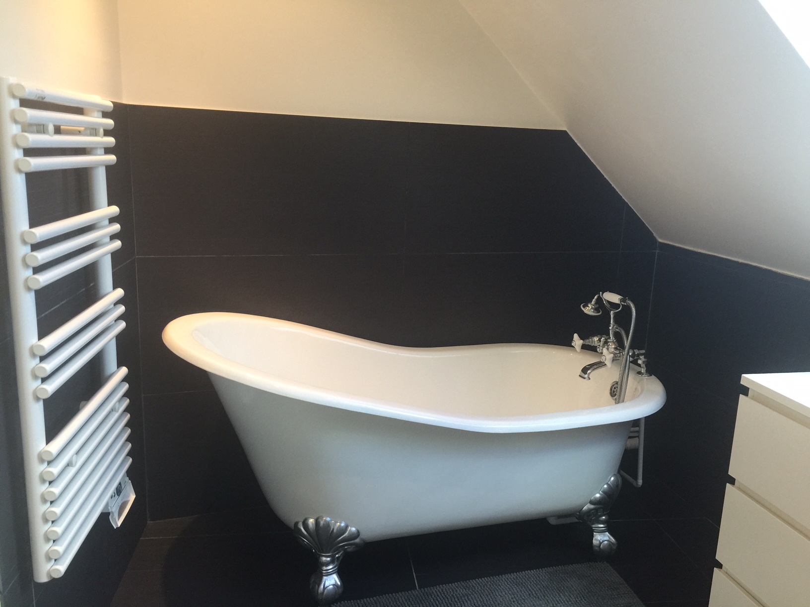 Salle de bains rénovée à Montreuil avec baignoire rétro sur pieds et mur en carrelage noir mat