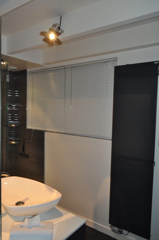 Salle de bains parentale à Vincennes – vasque ovale et radiateur noir mat Salle de bains parentale à Vincennes avec vasque ovale blanche et radiateur mural noir mat
