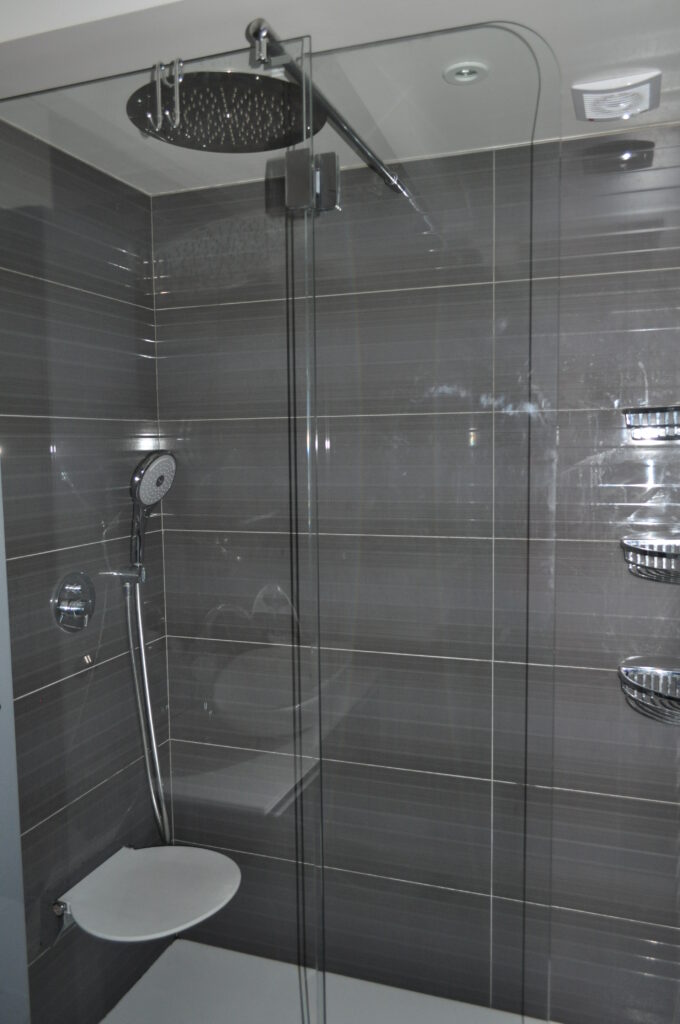 Salle de bains parentale à Vincennes – douche contemporaine et finitions gris brillant Salle de bains parentale à Vincennes avec carrelage gris brillant et douche moderne avec assise intégrée
