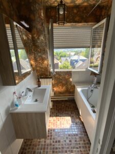 Salle de bains avec baignoire et lavabo avant rénovation en architecture d’intérieur, murs à motifs et carrelage ancien.