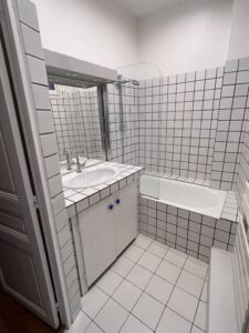 Salle de bains avec baignoire et meuble vasque carrelés, avant intervention d’un décorateur d’intérieur.