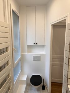 WC suspendus rénovés avec abattant noir et meuble de rangement intégré, salle de bains modernisée.
