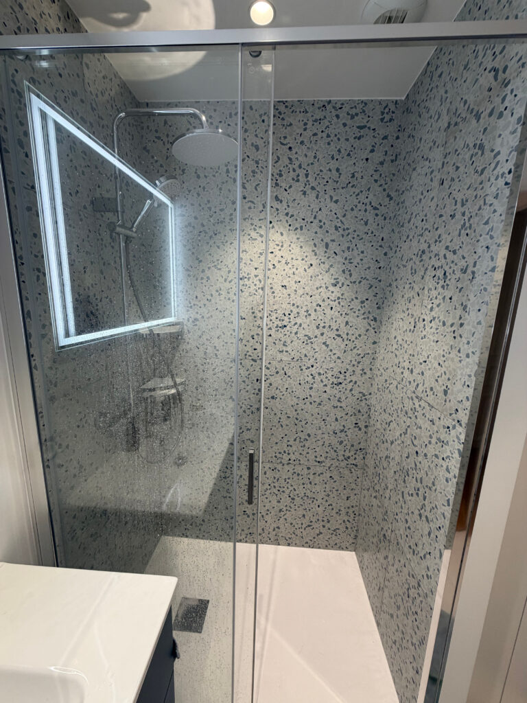 Douche italienne avec carrelage terrazzo et paroi vitrée