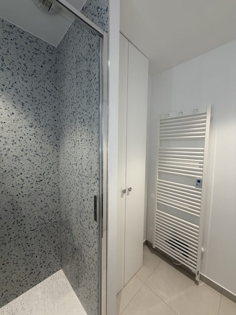 Placard blanc intégré et sèche-serviettes mural dans une salle de bains rénovée