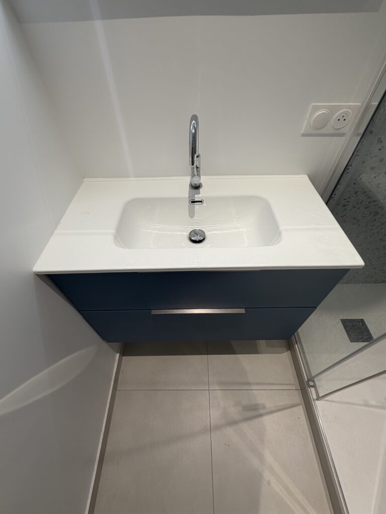 Gros plan sur le meuble vasque suspendu bleu dans une salle de bains contemporaine à Paris 9