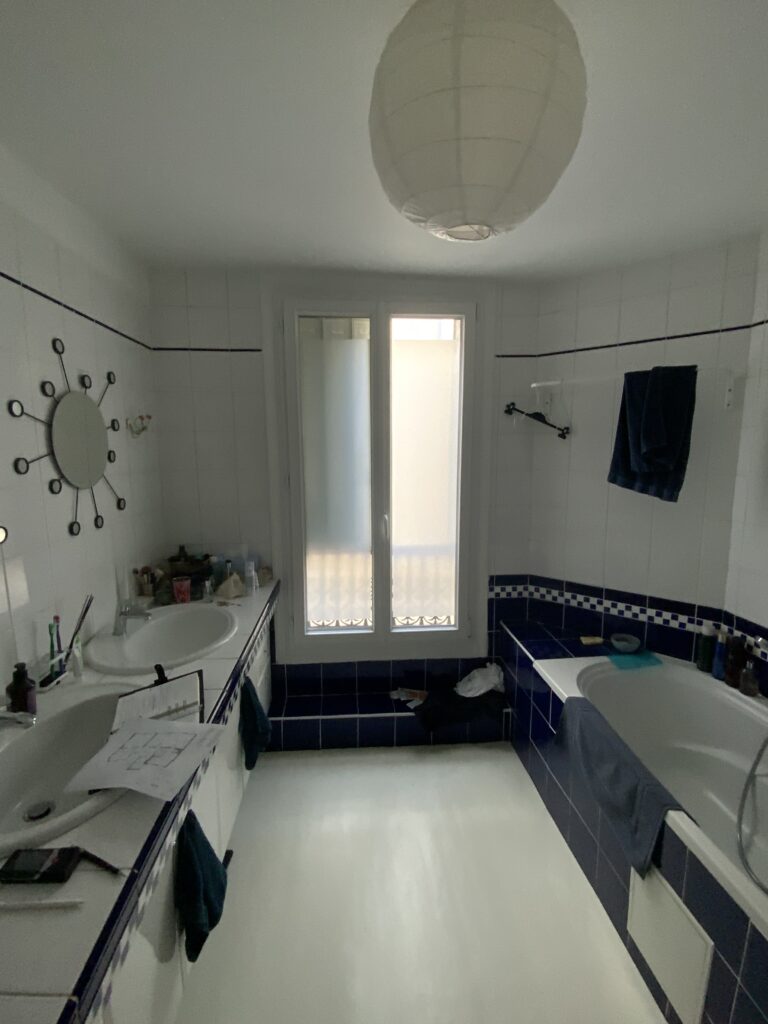 Salle de bains avec double vasque, baignoire et carrelage mural bleu et blanc