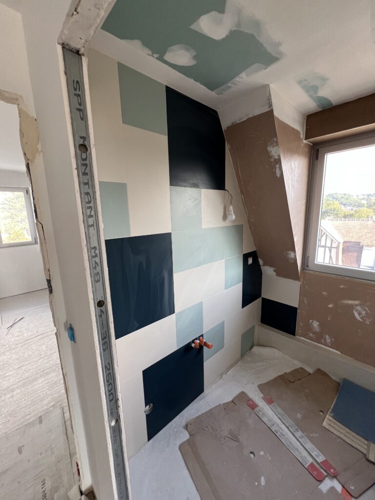 Carrelage mural en cours de pose dans la zone douche sous combles