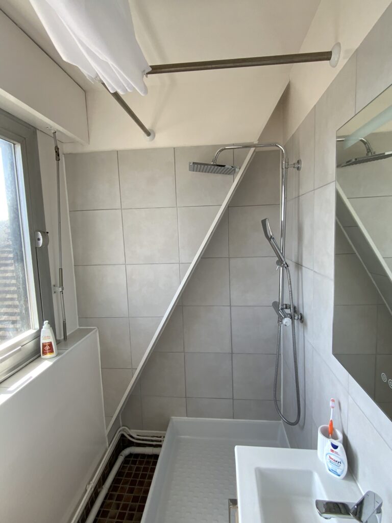Douche installée sous pente dans une petite salle de bains avant rénovation