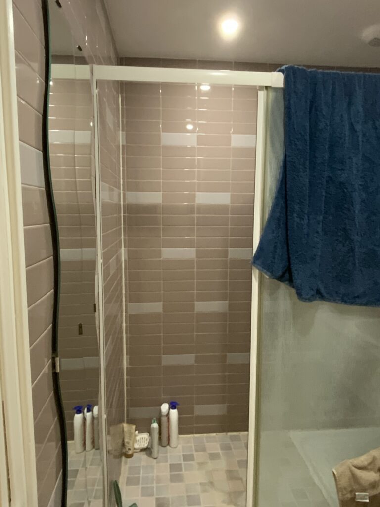 Vue du mur carrelé à l’intérieur de la douche, avant rénovation à Paris 9.