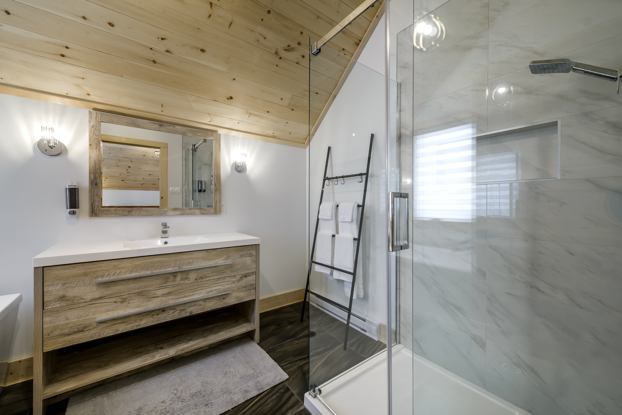 Salle de bains en chalet de montagne avec plafond bois, douche vitrée et aménagement optimisé en Isère
