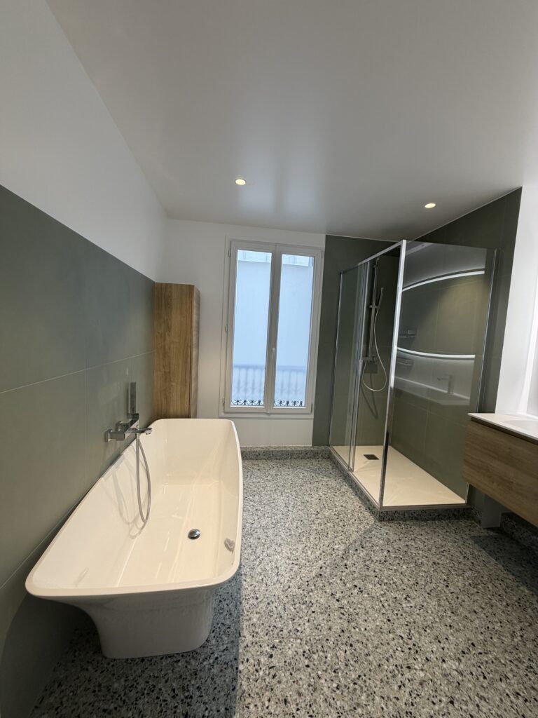 Salle de bains rénovée à Paris 9 avec baignoire, douche, vasque et terrazzo