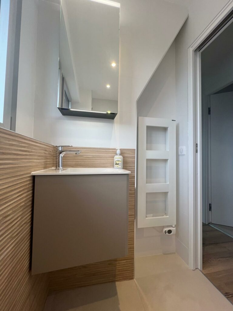 Salle de bains sous combles rénovée avec lave-mains suspendu et faïence effet bois Deauville
