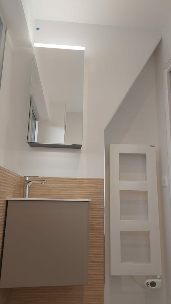 Meuble vasque compact et radiateur mural dans une petite salle de bains sous pente