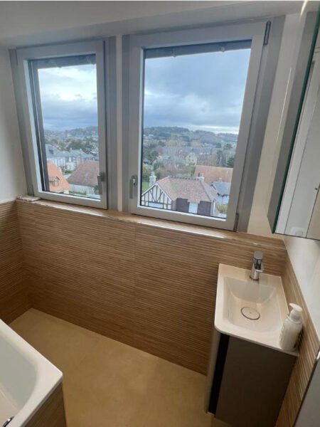 Vue d’ensemble d’une petite salle de bains sous combles rénovée avec baignoire, vasque et carrelage clair à Deauville