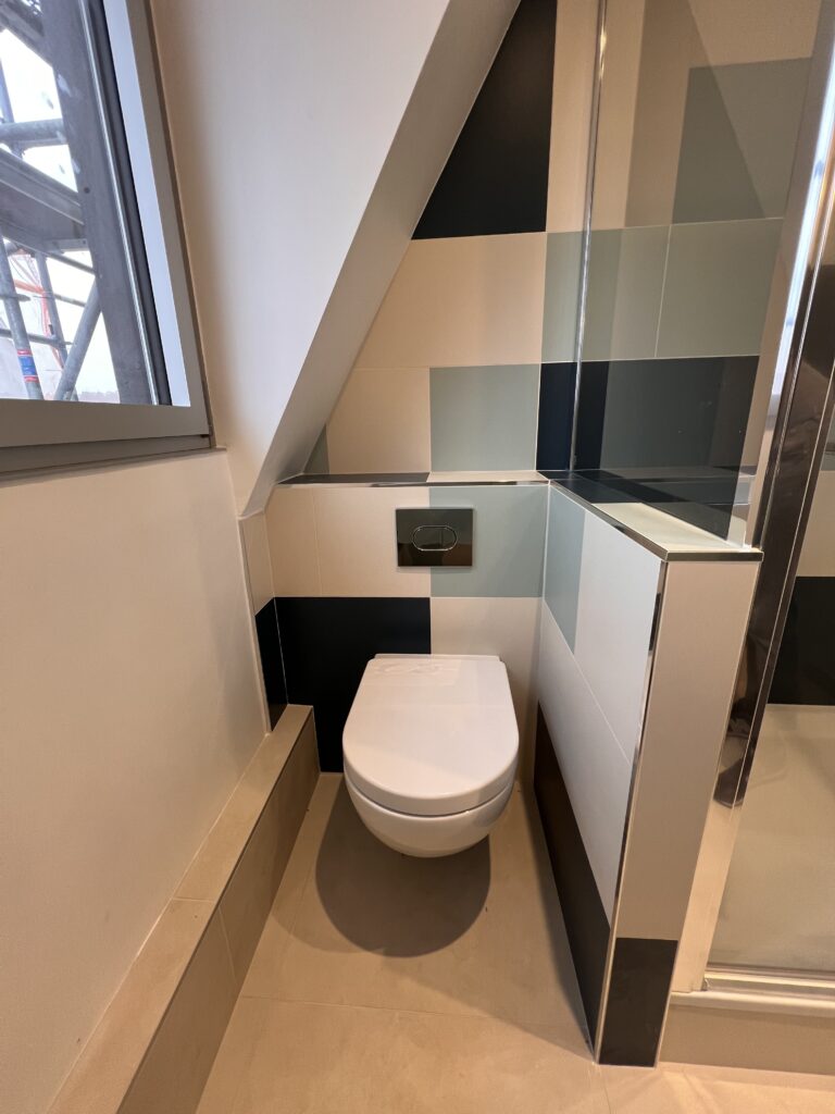 WC suspendu installé sous une pente de toiture dans une salle de douche moderne